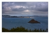 ein Sonnenstrahl fällt durch die dunklen Wolken kurz auf die Insel Île St-Rion, Pointe de Bilfot, Plouézec, Côtes-d’Armor, Bretagne